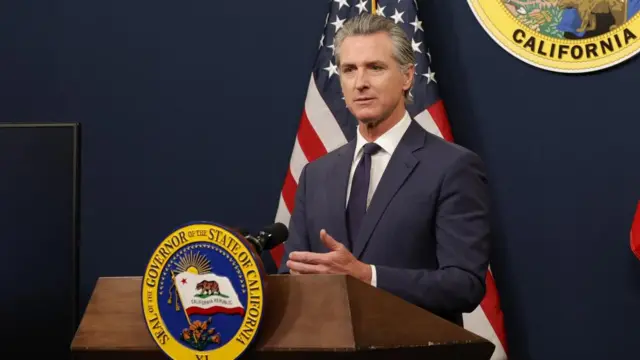 California Governor Gavin Newsom stands at a podium with the Governor of the State of California emblem in front