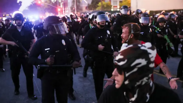 A demonstrator gestures to police officers, during protests against federal immigration sweeps, in Los Angeles