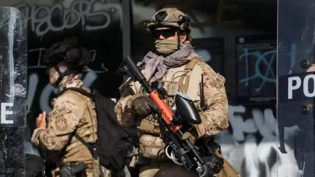 Members of law enforcement stand guard during a protest against federal immigration sweeps in downtown Los Angeles,