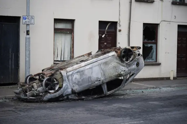 A car burnt out on its roof in a street