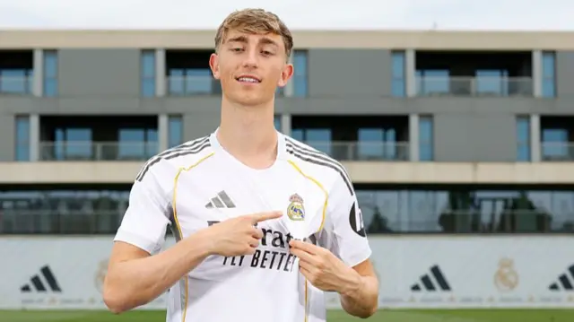 Dean Huijsen points to the Real Madrid badge