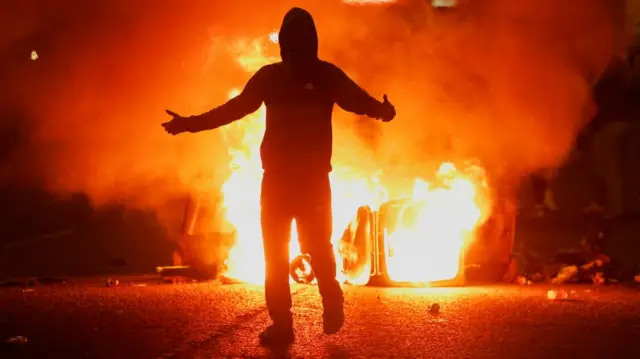 Fire burns near a demonstrator as riots continue in Ballymena, Northern Ireland, June 11, 2025