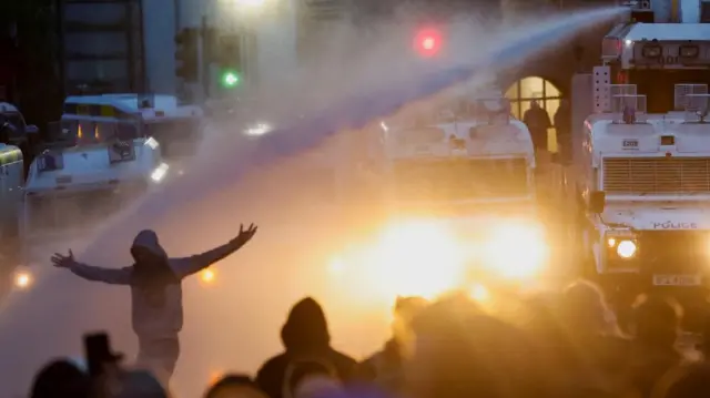 Police aim a water cannon at demonstrators as riots continue in Ballymena, Northern Ireland, June 11, 2025