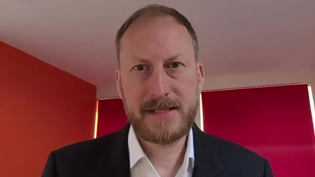 Carl Emmerson on a video call from his home against a red wall and white ceiling