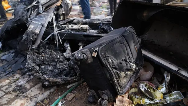 Debris at the site of a plane crash, including a black suitcase