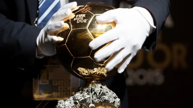 A volunteer places the FIFA Ballon d'Or trophy on a display