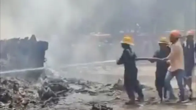 A screengrab from the video shows firefighters and people in civilian clothes spraying water on the wreckage