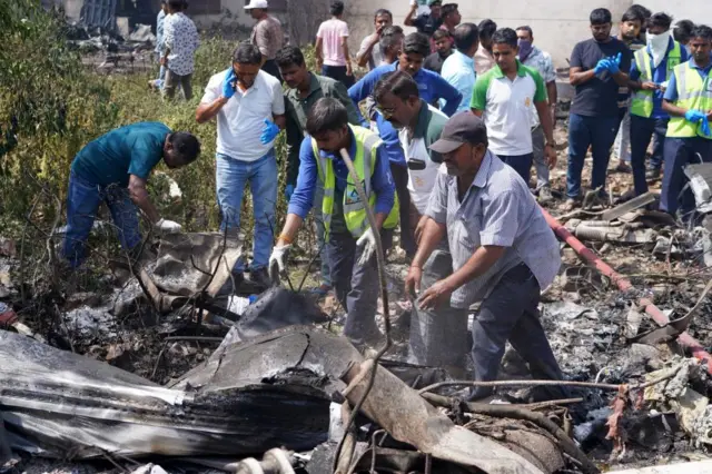 Officials inspect the site of a plane crash near Sardar Vallabhbhai Patel International Airport in Ahmedabad