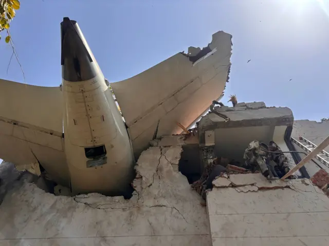 Plane sticking out the side of a building.