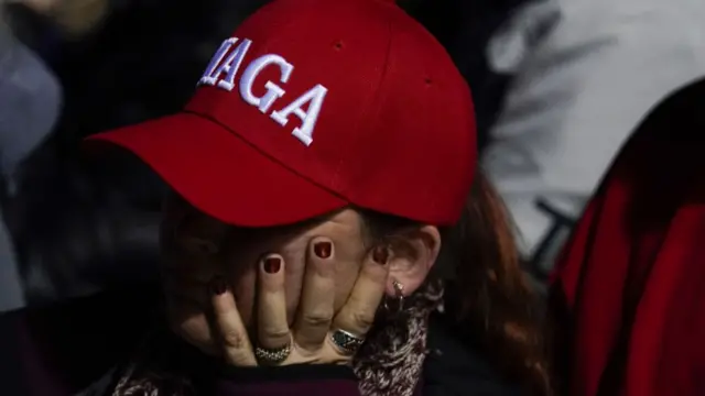 A woman wears a red Maga cap