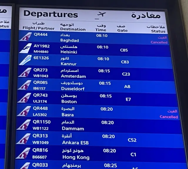 A departures board shows flights to Basra and Baghdad both cancelled.