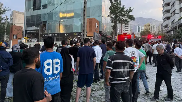 A crowd of mostly men stand on a road