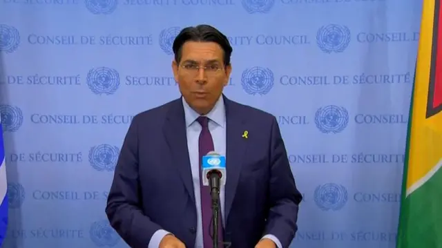 Headshot of Danon talking in front of a blue background