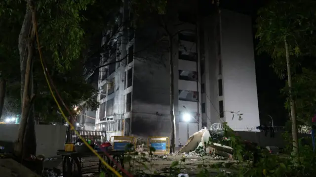 A damaged building in the dark with debris strewn across the floor.