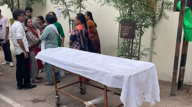 Grieving families stand outside the hospital in Ahmedabad