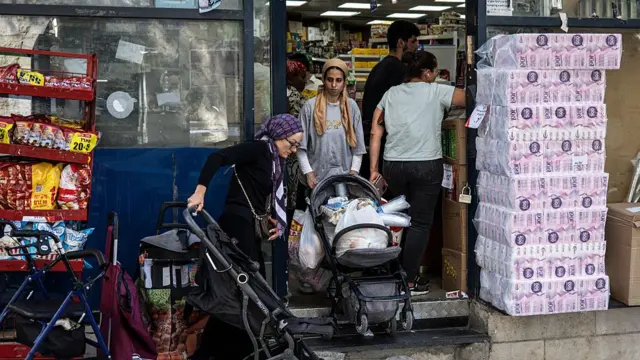 A woman pushes a stroller full with goods as people stock up with supplies, at a shop in Jerusalem, on June 13, 2025