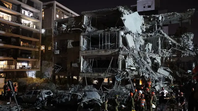 Israeli soldiers and first responders assess the damage to a building hit by an Iranian missile in the town of Ramat Gan, just east of Tel Aviv