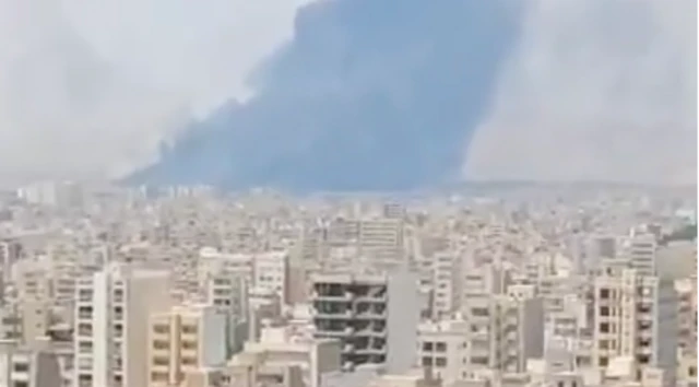 A large plume of dark smoke rises from a residential area