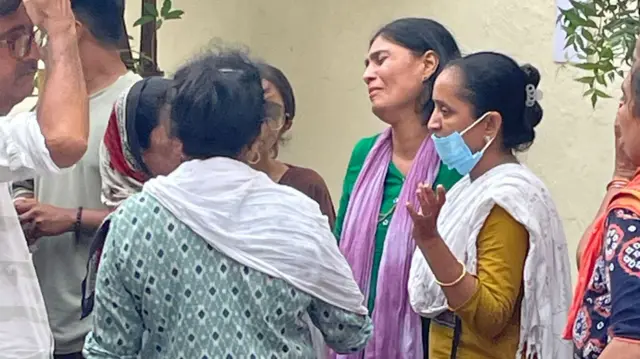 Grieving families stand outside the hospital in Ahmedabad
