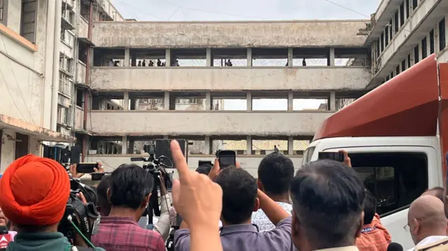 People holding their phones, trying to capture a building.