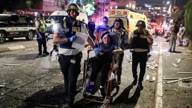Rescuers evacuate an injured woman in the town of Ramat Gan, just east of Tel Aviv