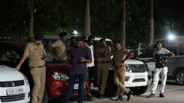 A group of men stand around cars at night at the Civil Hospital in Ahmedabad.
