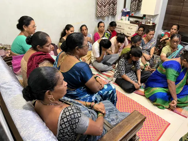 Women sit on the floor in a room to remember Air India cabin crew member Maithili Patil