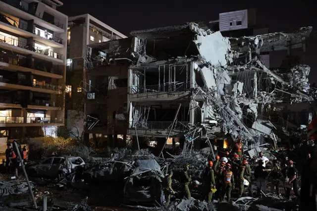 Israeli soldiers and first responders assess the damage to a building hit by an Iranian missile in the town of Ramat Gan, just east of Tel Aviv