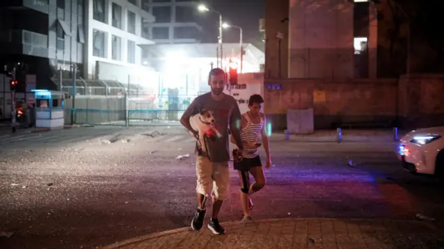 Israelis react at an impact site following a missile attack from Iran on Israel, at Tel Aviv