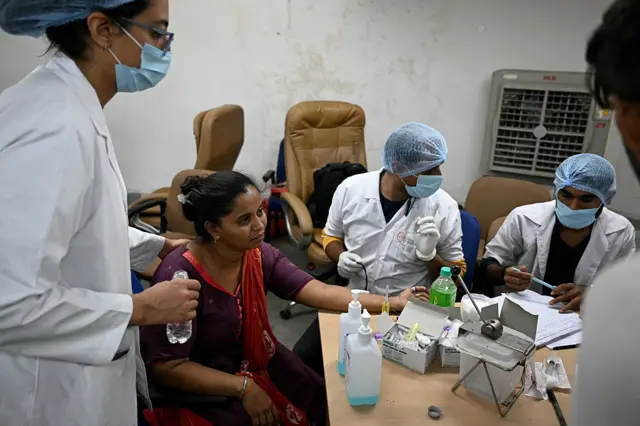 Medical officials console as they collect DNA samples from a relative, so that her loved ones can be identified, at an emergency centre in Ahmedabad on June 13, 2025,