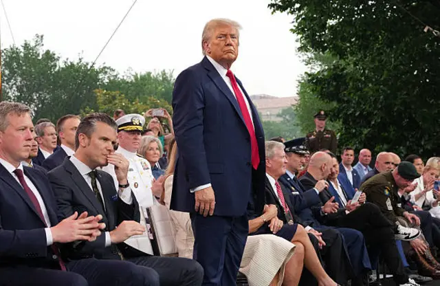 Trump stands and watches the parade