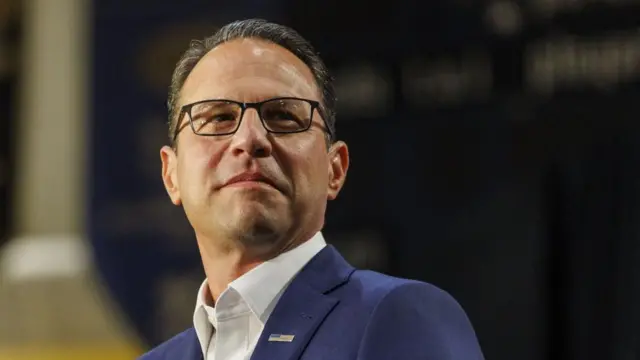 Josh Shapiro looks on wearing glasses.