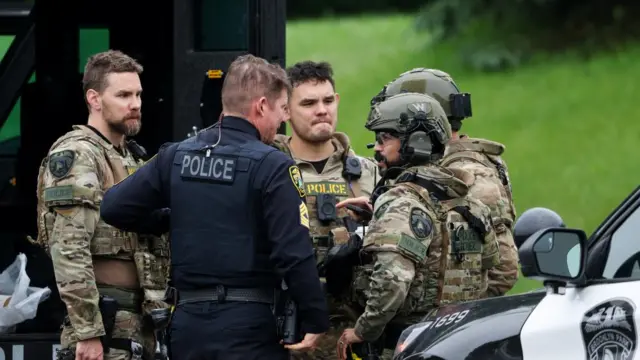 Officers communicate in a staging area after what police said was a targeted shooting in the area around Edinburgh Golf Course in the Minneapolis suburb of Brooklyn Park.