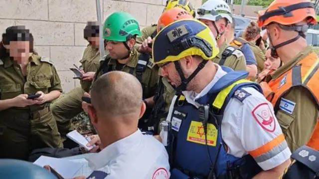 First responders wearing uniforms and helmets stand in front of a desk