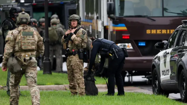 Police officers, some wearing military-style camouflage, and vehicles