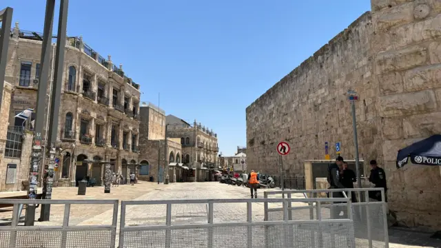 streets are empty in the old city. an empty roadway can be seen beyond steel gates