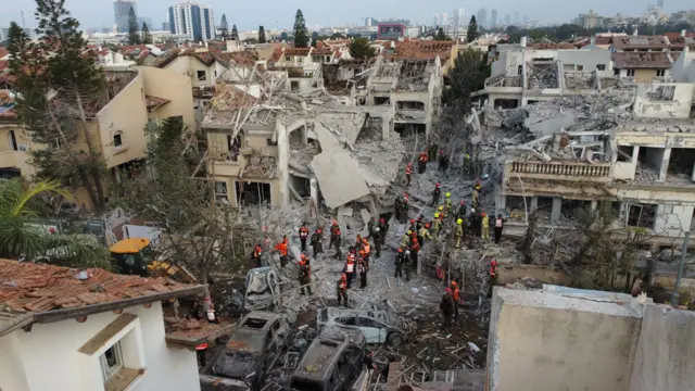 Ekipet izraelite të shpëtimit në vendin ku një raketë balistike iraniane goditi ndërtesat e banimit në Rishon LeZion, pranë Tel Avivit, Izrael, 14 qershor 2025