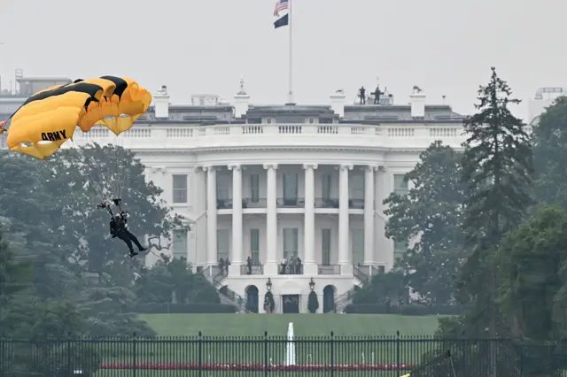 Paratrooper mid-air prepares to land. The White House is in the background