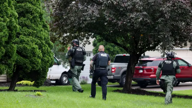 Police officers wearing bulletproof vests walk on a lawn