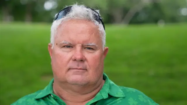 Steven Jewell is wearing a green shirt and has sunglasses resting on his head.