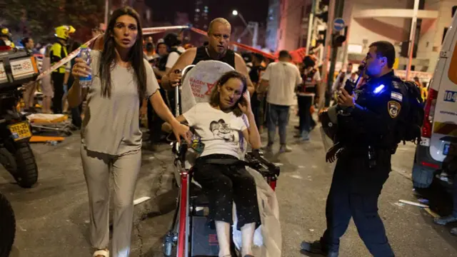 Israelis evacuate after an attack on residential buildings in the city of Bat Yam