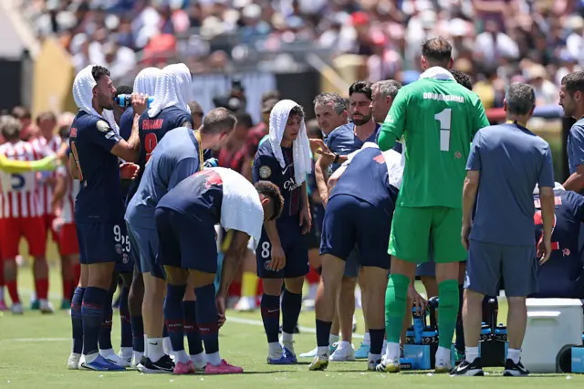 PSG players put cold wet towels on their heads as they take on fluids during a cooling break