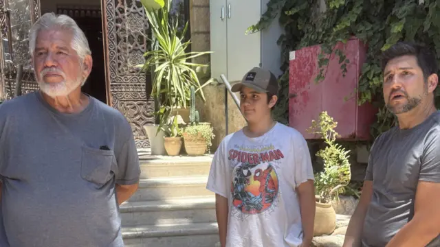Deux hommes et garçons en t-shirts gris sont debout.
