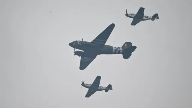 Three historic US Army planes with white and blue star decals near their tails and white stripes on the underside of their wings.