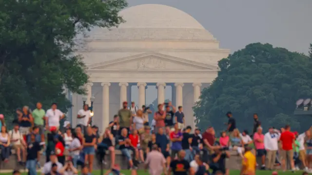 A few dozen people watch the parade in front of the white domed Jefferson Memorial