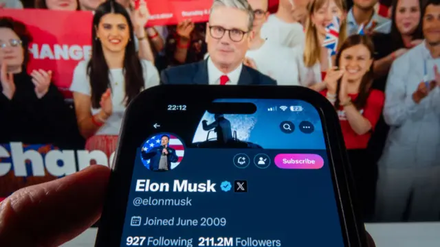 In this photo illustration the profile page of tech billionaire Elon Musk owner of US online social media and social networking site 'X' is displayed on a smartphone screen in front of the opening website page of the Labour Party website