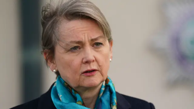 Home Secretary Yvette Cooper wears a blue jacket and has a silk blue scarf around her neck