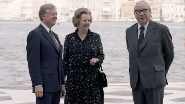 Jimmy Carter, Minister Margaret Thatcher and Roy Jenkins stand together in front of a river.