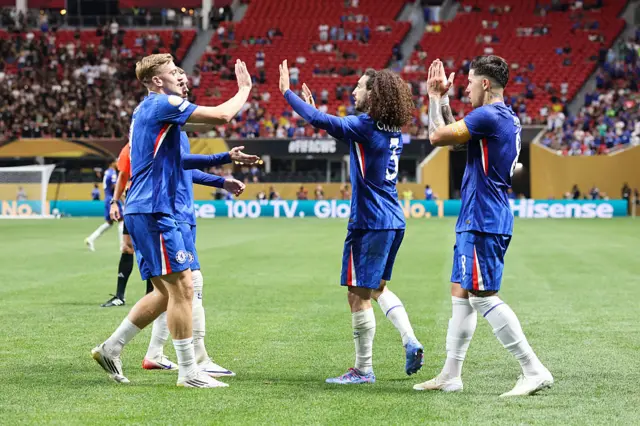 Chelsea players celebrate goal as the stands are half empty in the background