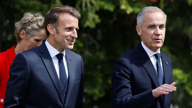 French President Emmanuel Macron, wearing a dark suit, stands beside Mark Carney.